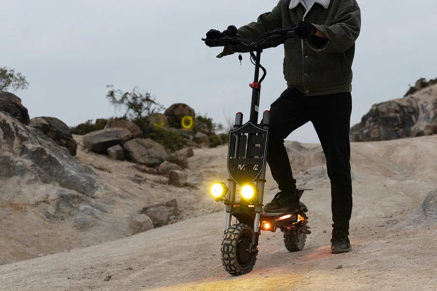 Electric scooter with headlights on at dusk on a rocky off-road trail