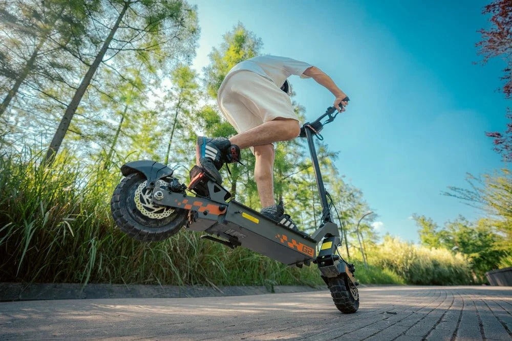 Rider jumping a black KuKirin electric scooter with orange details off a kerb – KuKirin G2 Pro vs G4 vs G2 Master