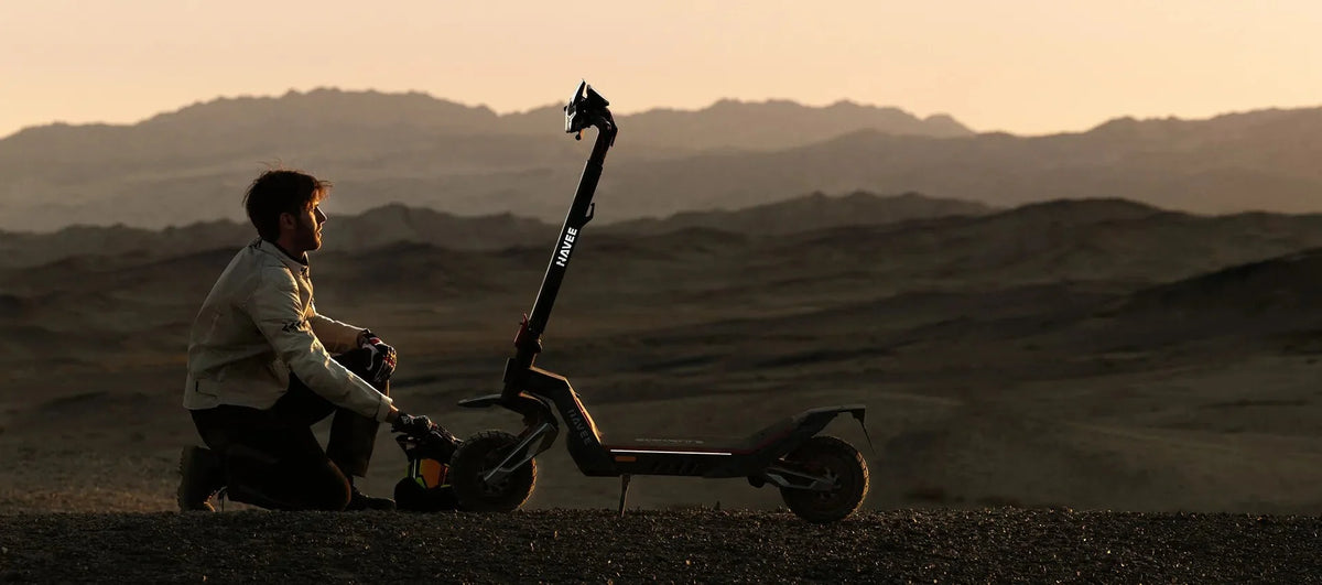 Man kneeling beside his electric scooter at dusk, checking it over – how to lower the risk of an electric scooter fire