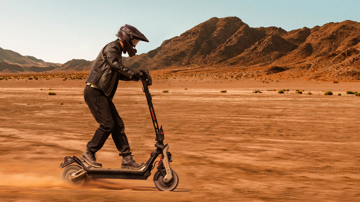 Rider in helmet and leather jacket on a Ninebot GT3 e-scooter on a sandy plain – e-scooter for heavy adults