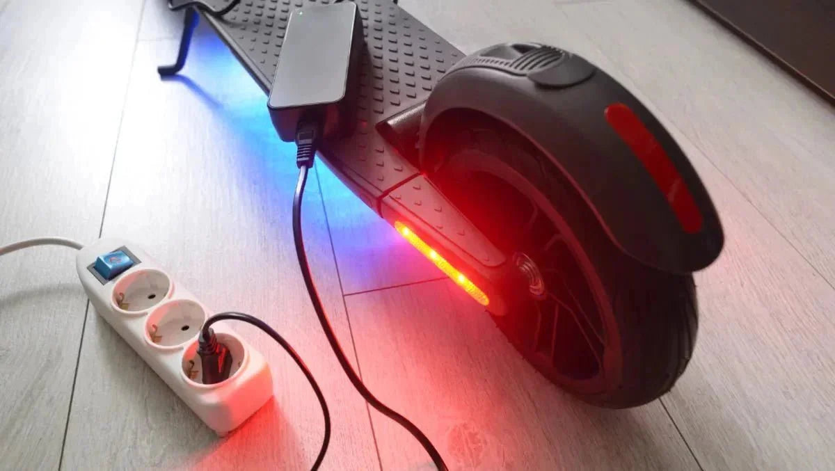 Electric scooter charging indoors with the charger plugged into a power strip – how to increase e-scooter range