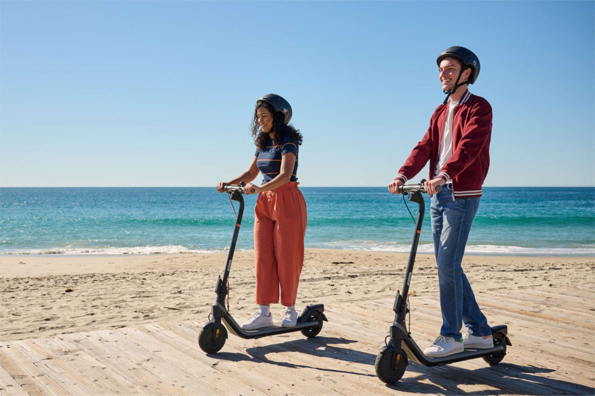 Two riders in helmets on electric scooters on a seaside boardwalk – electric scooter laws in Europe