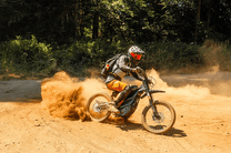 Person riding the 79BIKE Falcon Pro electric dirt bike on sandy ground