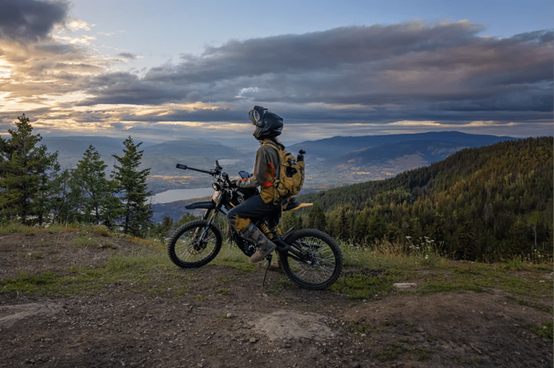 Person standing with the 79BIKE Falcon Pro electric dirt bike on a grassy field