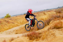 Person riding the 79BIKE Falcon Pro electric dirt bike on a grassy field