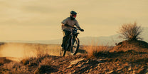 Person riding the 79BIKE Falcon Pro electric dirt bike on a grassy field at sunset