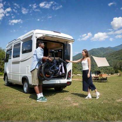 ENGWE O20 Boost – man lifting a folded bike into a white motorhome while a woman stands beside him, meadow and mountains in the background