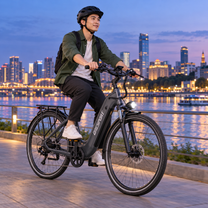 Man riding a grey OneSport OT05 Max by a river at dusk with a city skyline in the background