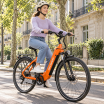 Woman wearing a helmet riding an orange OneSport OT05 Max on a street with trees and building facades