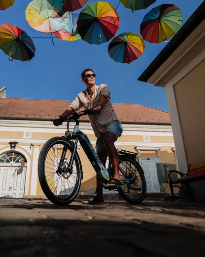 OneSport WT05 with a man standing over the bike on a cobblestone street under colourful umbrellas
