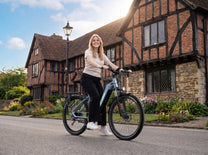 Smiling woman on OneSport WT05 on a road in front of a brick half-timbered house