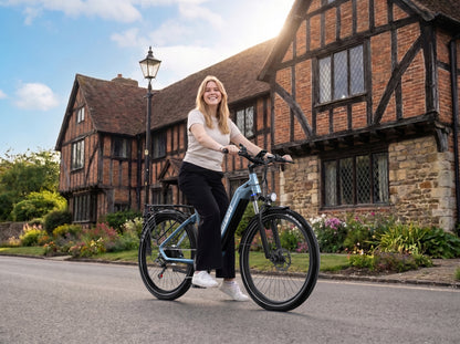 Smiling woman on OneSport WT05 on a road in front of a brick half-timbered house