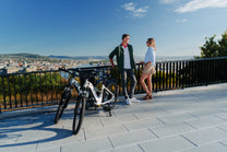 OneSport WT05 parked by a black railing with a couple talking and a city view in the background