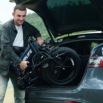 Smiling man loading a folded URLIFE T5 into a car boot
