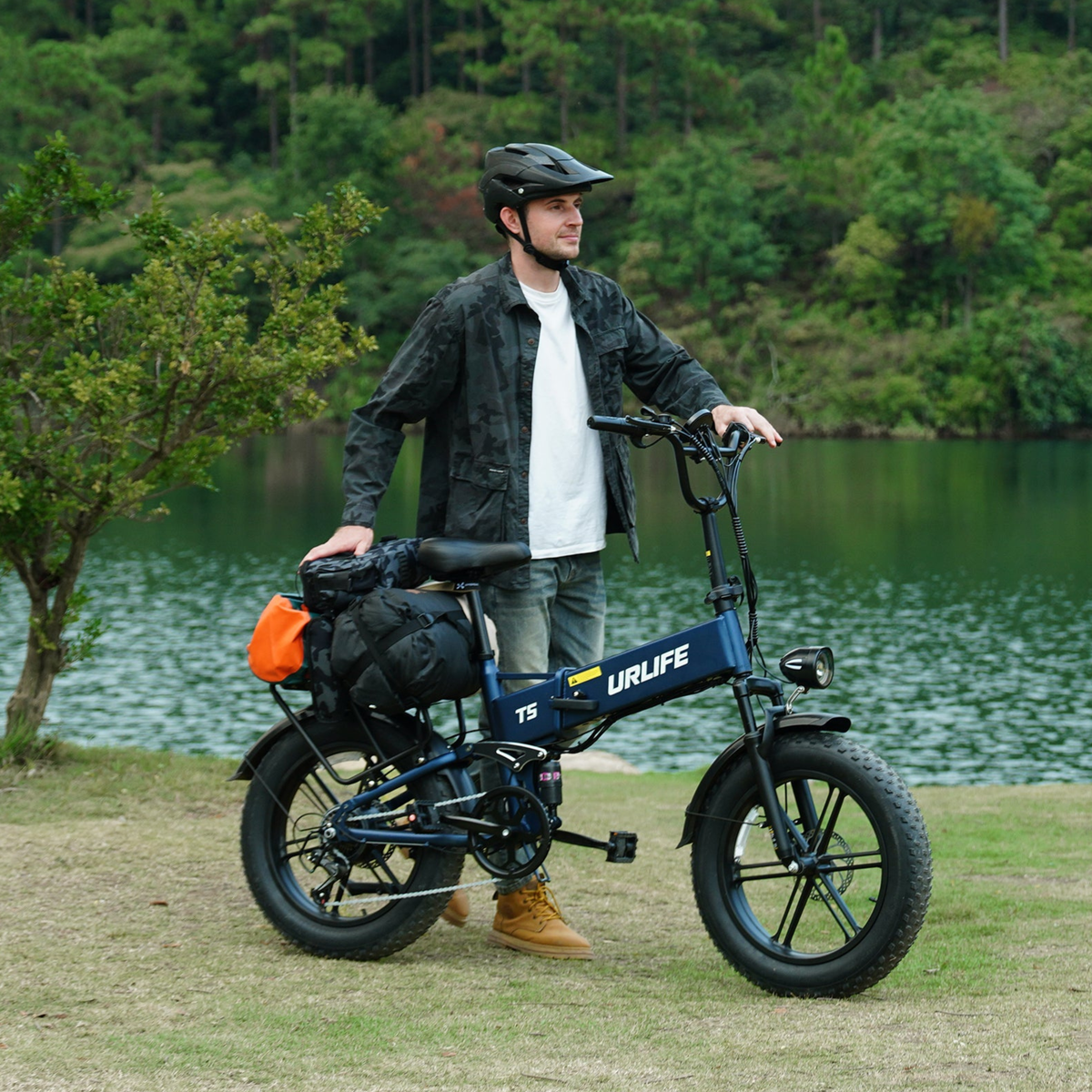 Blue URLIFE T5 with bags on the rear rack by a lake, person standing next to it