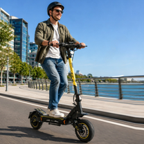 Man wearing a helmet rides a Wheely - H7 electric scooter along a quay by the water