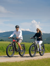 Two riders with the Duotts F26 Lite fat-tyre e-bike on a grassy field