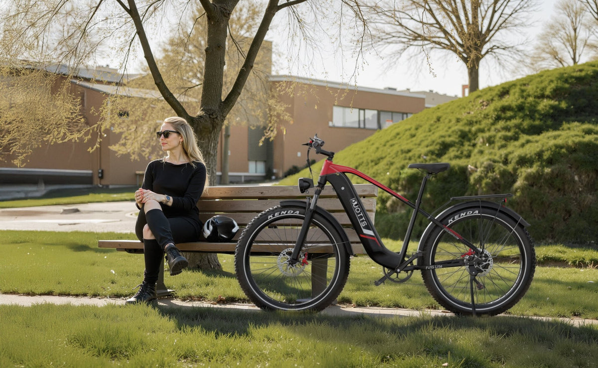 Person sitting next to the Duotts F26 Lite fat-tyre e-bike in a park