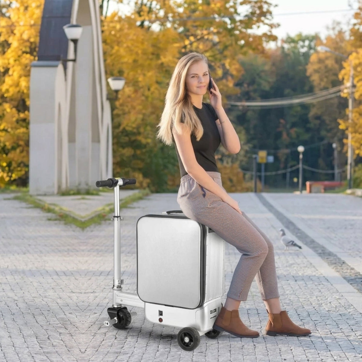 Person sitting on the AeroDrive Edition electric ride-on suitcase in autumn