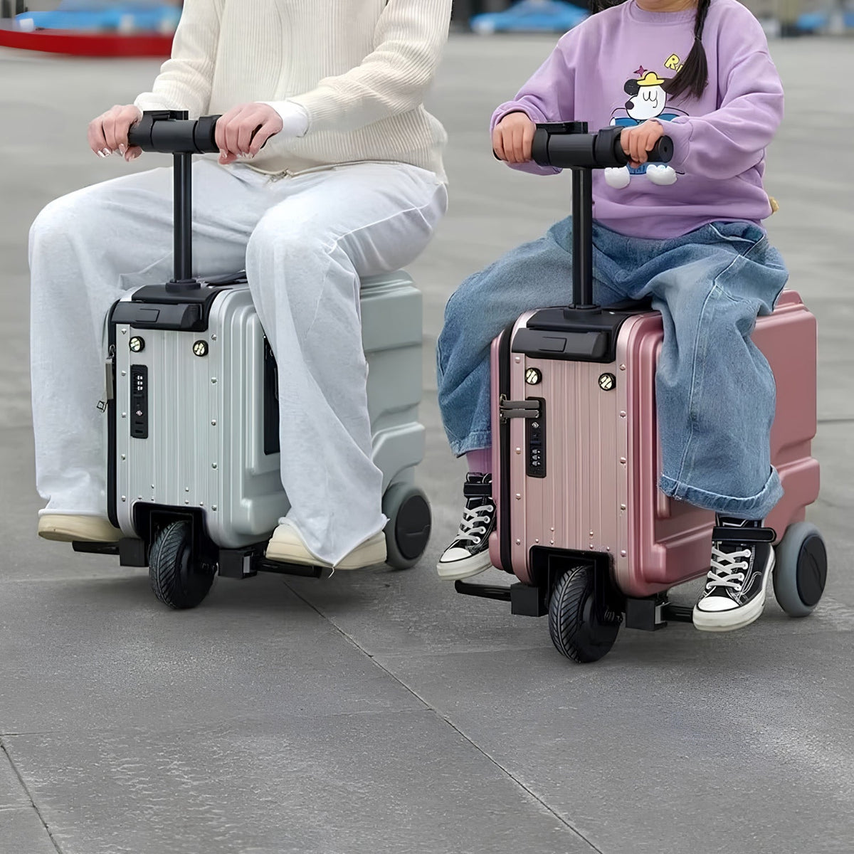 Two people each riding a PowerDrive Pro Edition electric ride-on suitcase