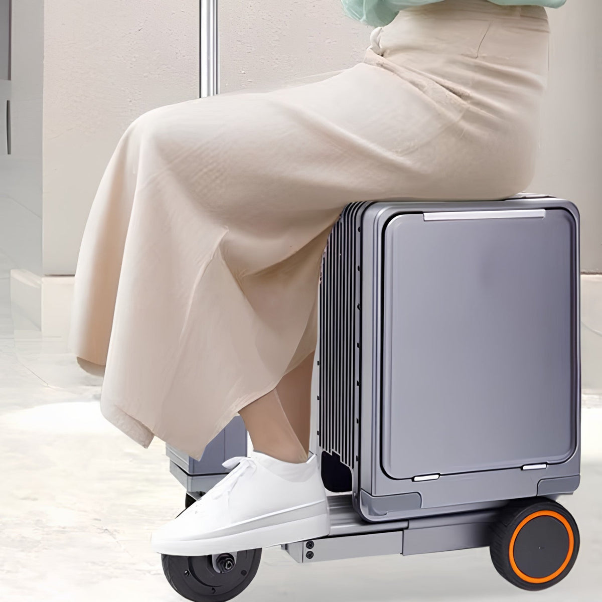 Person riding the Urban Move Edition electric ride-on suitcase in silver indoors