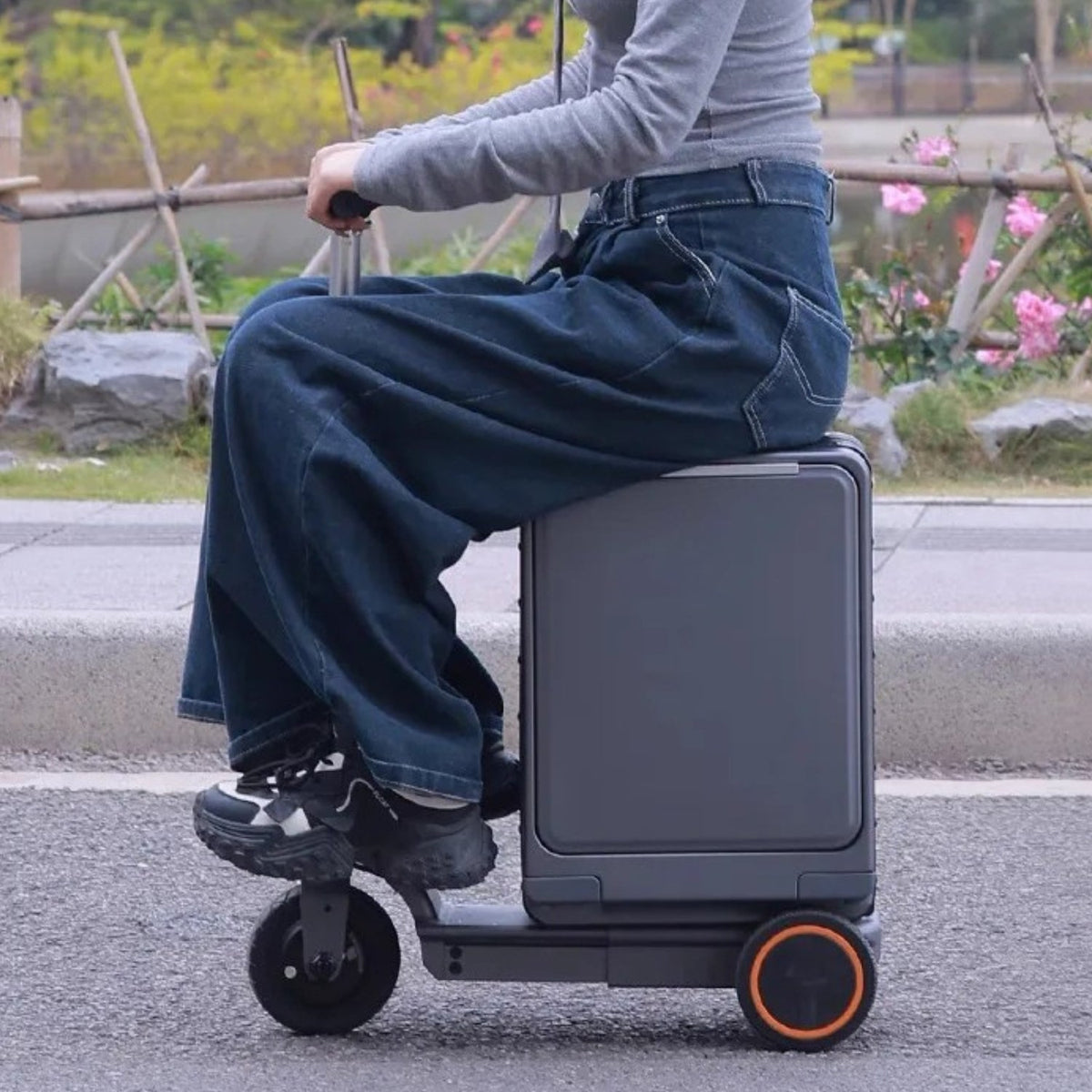 Person riding the Urban Move Edition electric ride-on suitcase in black outdoors