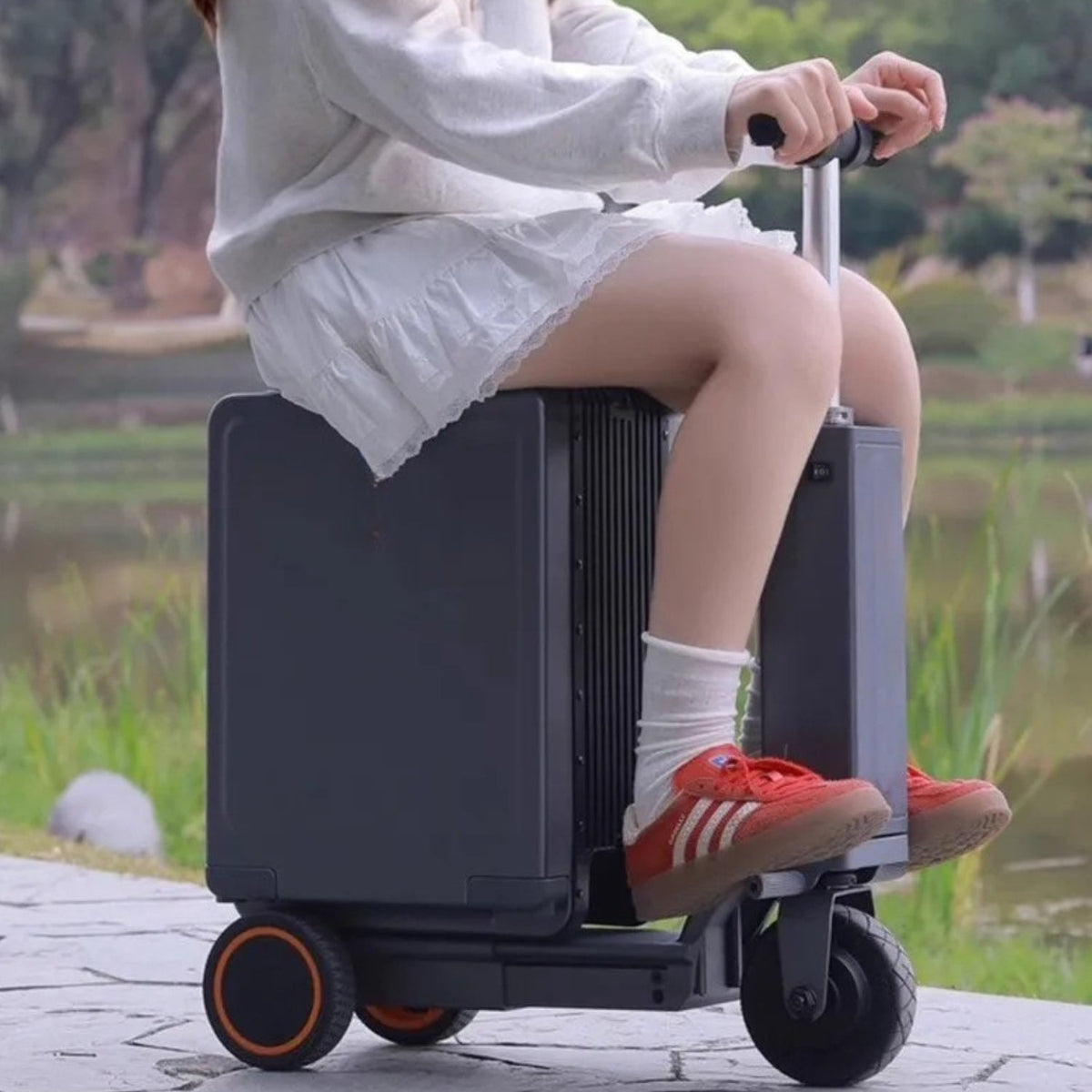 Person riding the Urban Move Edition electric ride-on suitcase in black outdoors