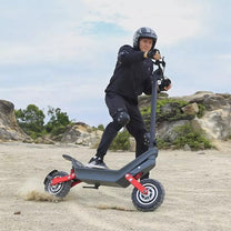 Man riding the HX X10 electric scooter on sandy ground