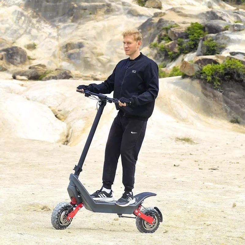 Man standing with the HX X10 electric scooter on sandy ground