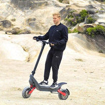 Man standing with the HX X10 electric scooter on sandy ground