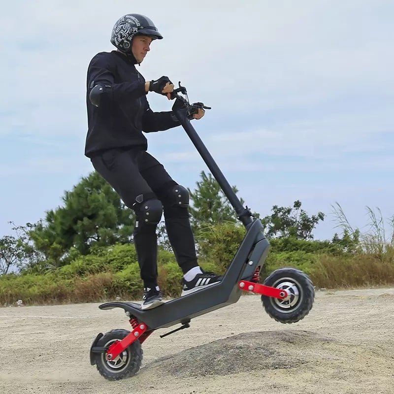 Man riding the HX X10 electric scooter on sandy ground