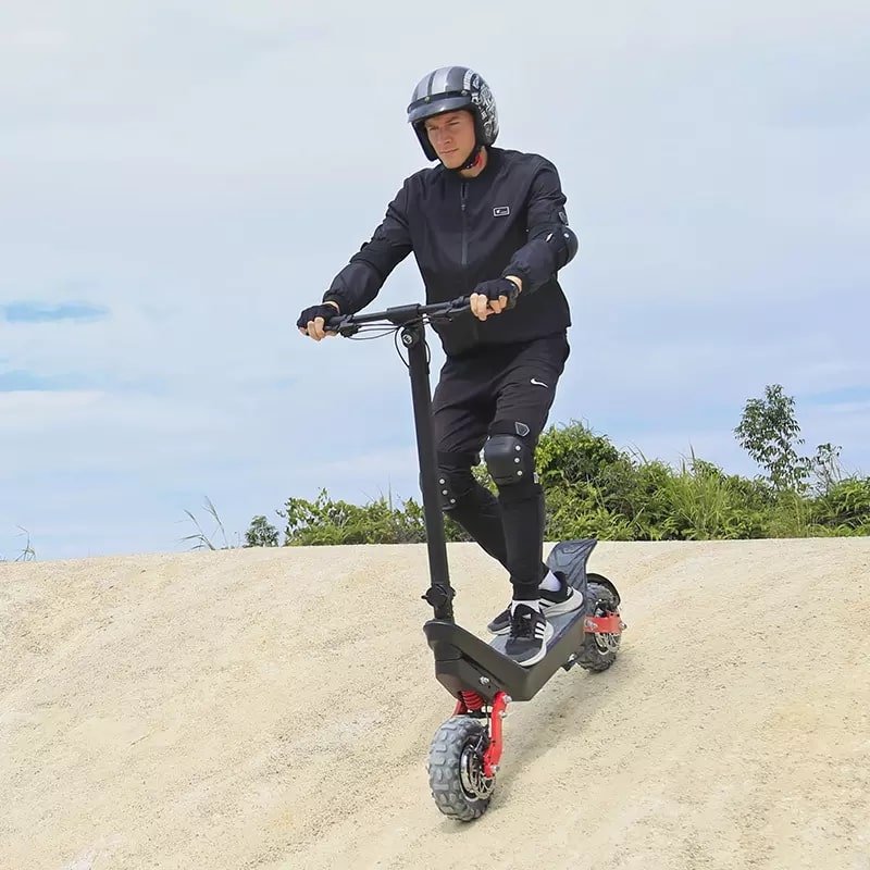 Man riding the HX X10 electric scooter on sandy ground