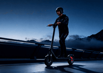 Man riding the HX X9B electric scooter in an evening setting