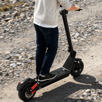 Man riding the HX X9B electric scooter on a gravel road