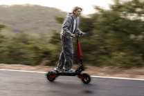 Person riding the KOOLUX U1 electric scooter on a road
