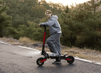 Person riding the KOOLUX U1 electric scooter on a road