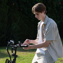 Man standing with the KOOLUX X8 fat-tyre e-bike on a grassy field