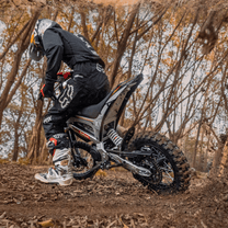 Rider taking the KuKirin X1 electric dirt bike off-road in the forest