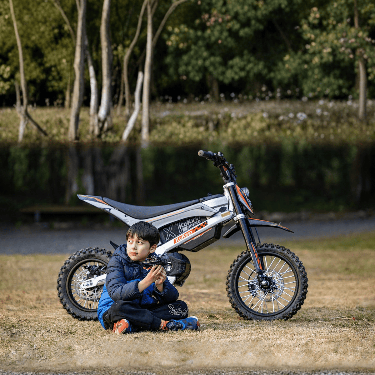 Person sitting next to the KuKirin X1 electric dirt bike with a child