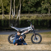 Person sitting next to the KuKirin X1 electric dirt bike with a child