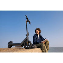 Person sitting next to the Segway Ninebot E2 Pro electric scooter