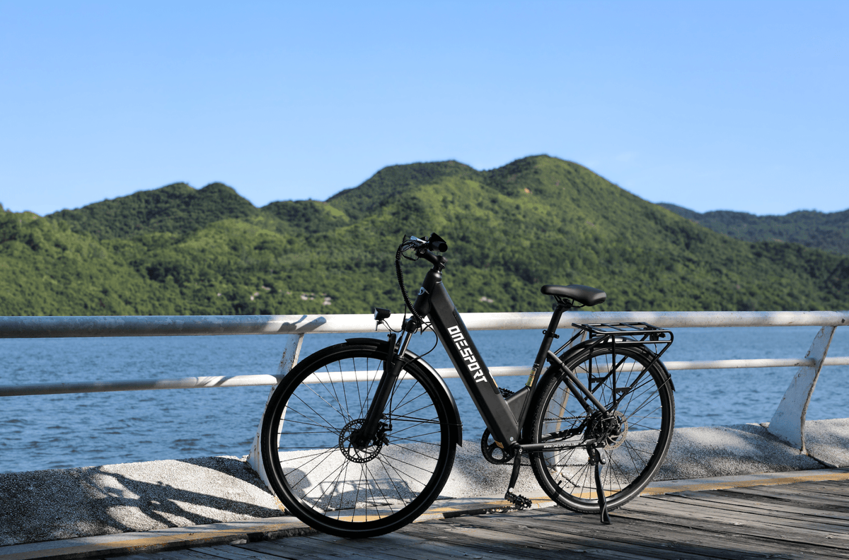 OneSport OT12 e-bike, front three-quarter view in black by the sea