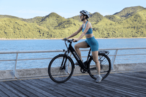 Woman sitting on the OneSport OT12 e-bike in black by the sea