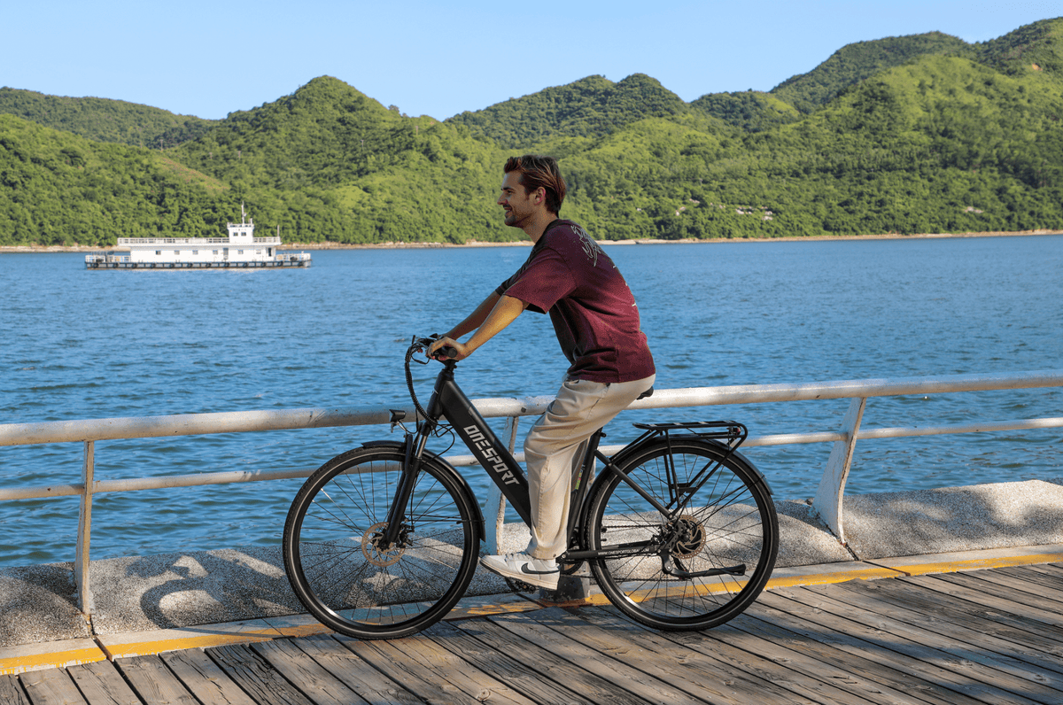 Person riding the OneSport OT12 e-bike in black by the sea