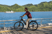 Person riding the OneSport OT12 e-bike in black by the sea