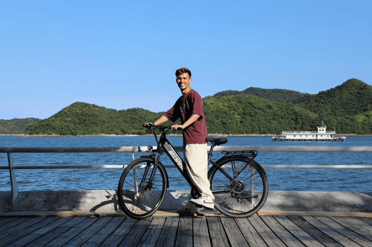 Man standing with the OneSport OT12 e-bike in black by the sea