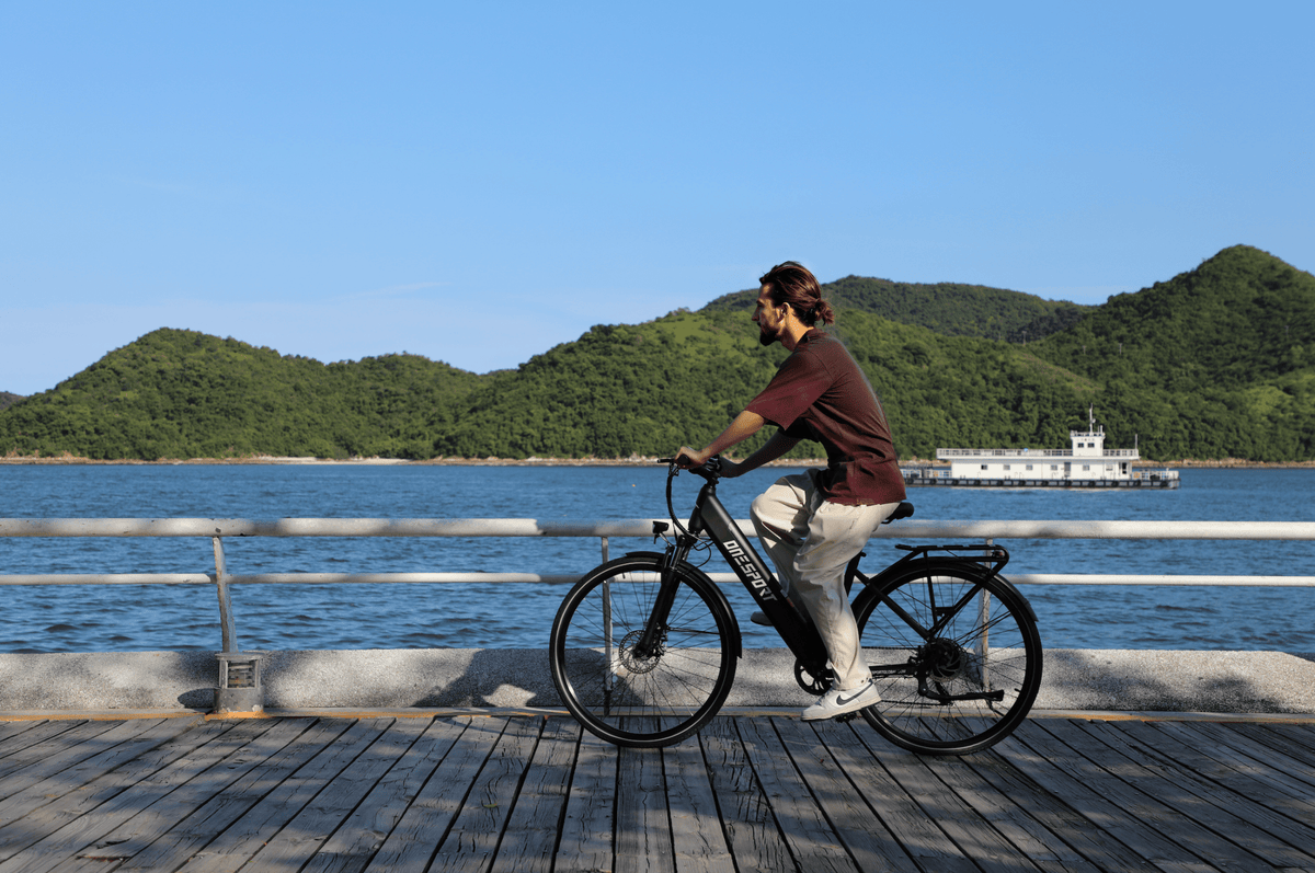Man riding the OneSport OT12 e-bike in black by the sea