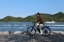 Man riding the OneSport OT12 e-bike in black by the sea