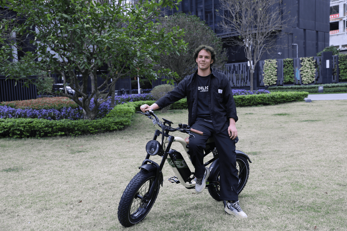 Man standing with the OneSport W66 fat-tyre e-bike on a grassy field