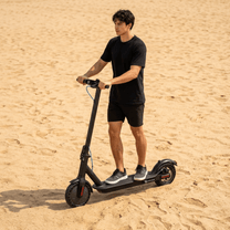 Man standing with the SEEDREAM RED WING MINI electric scooter on sandy ground